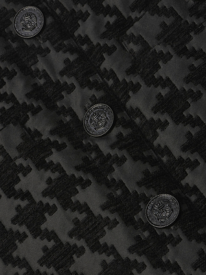 Close-up of the Mireya Houndstooth Mini Skirt by L'AGENCE, featuring a black jacquard houndstooth pattern and three decorative crest-embossed buttons.