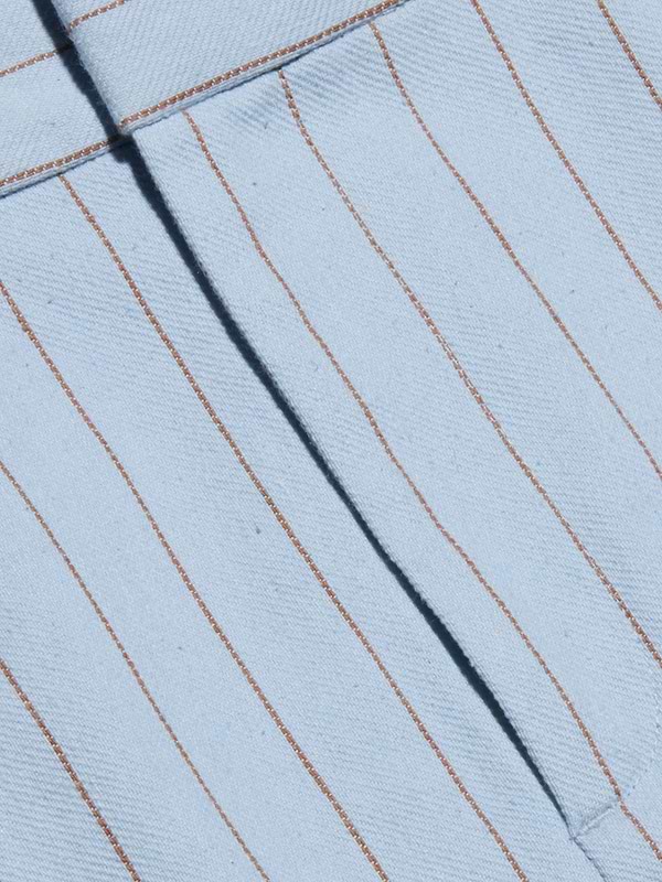 Close-up of the Vera Pinstriped Mini Skirt, crafted from a light blue cotton blend fabric featuring thin, evenly spaced vertical brown pinstripes and a visible seam running diagonally across the tailored silhouette.
