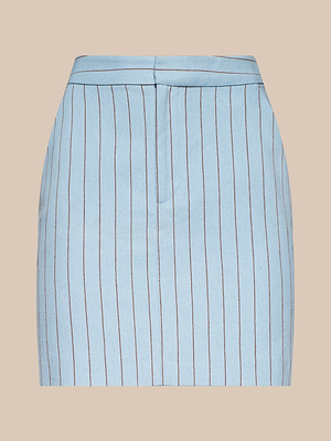 The Vera Pinstriped Mini Skirt, crafted from a light blue cotton blend with vertical dark stripes, features front seams and a zipper closure—ideal for warm-weather suiting. Shown against a beige background.