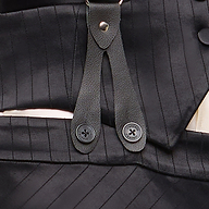 Close-up of the Vespera Suspender Maxi Skirt in black pinstripe, featuring a leather strap and two buttons attached to the waistband. The fabric’s vertical stripes and button stitching are visible, enhanced by the refined look of satin suiting.