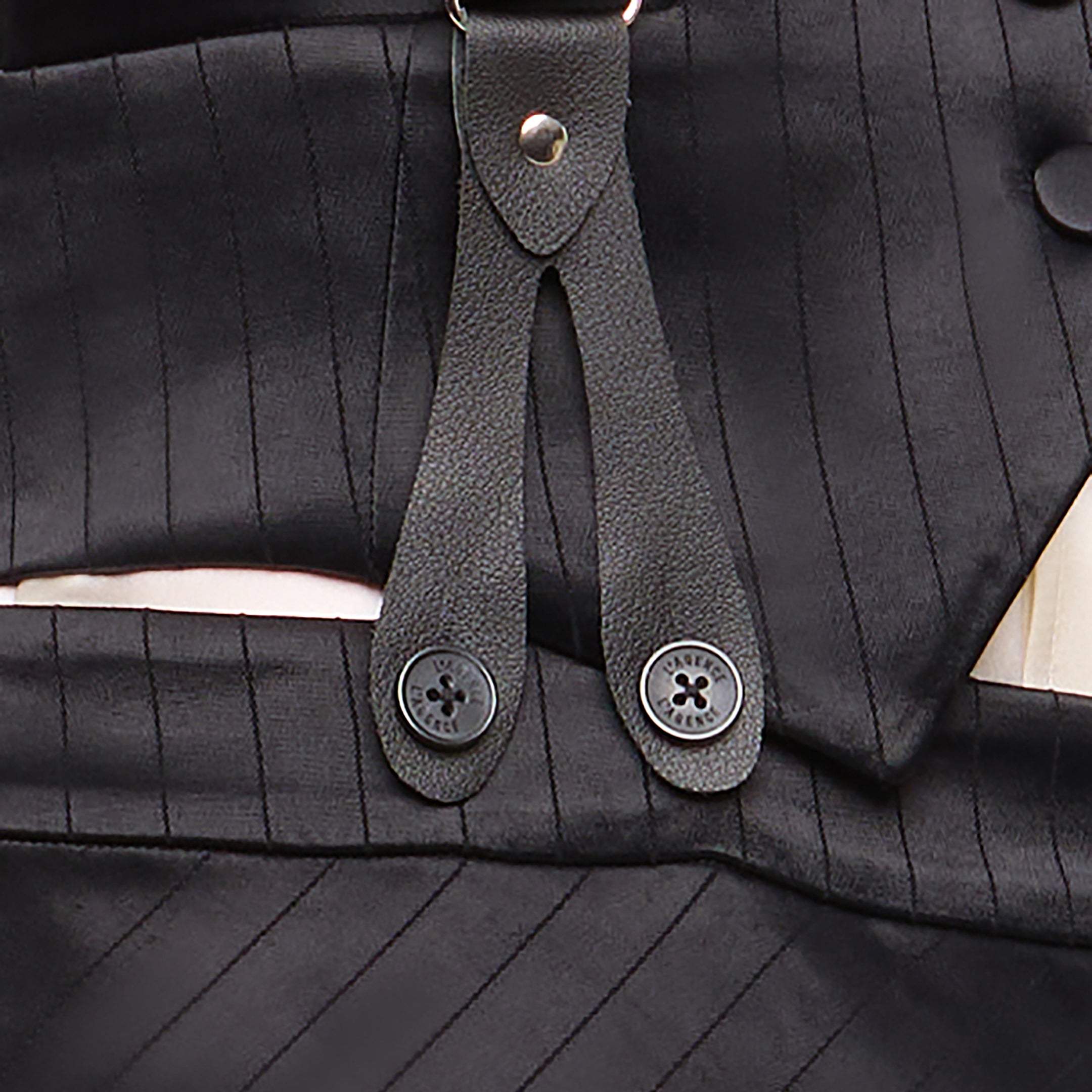 Close-up of the Vespera Suspender Maxi Skirt in black pinstripe, featuring a leather strap and two buttons attached to the waistband. The fabric’s vertical stripes and button stitching are visible, enhanced by the refined look of satin suiting.
