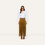 A person wearing a white button-down shirt, a double-buckle belt, and a Karoline Suede Fringe Skirt, which is a long brown tiered fringe statement piece.