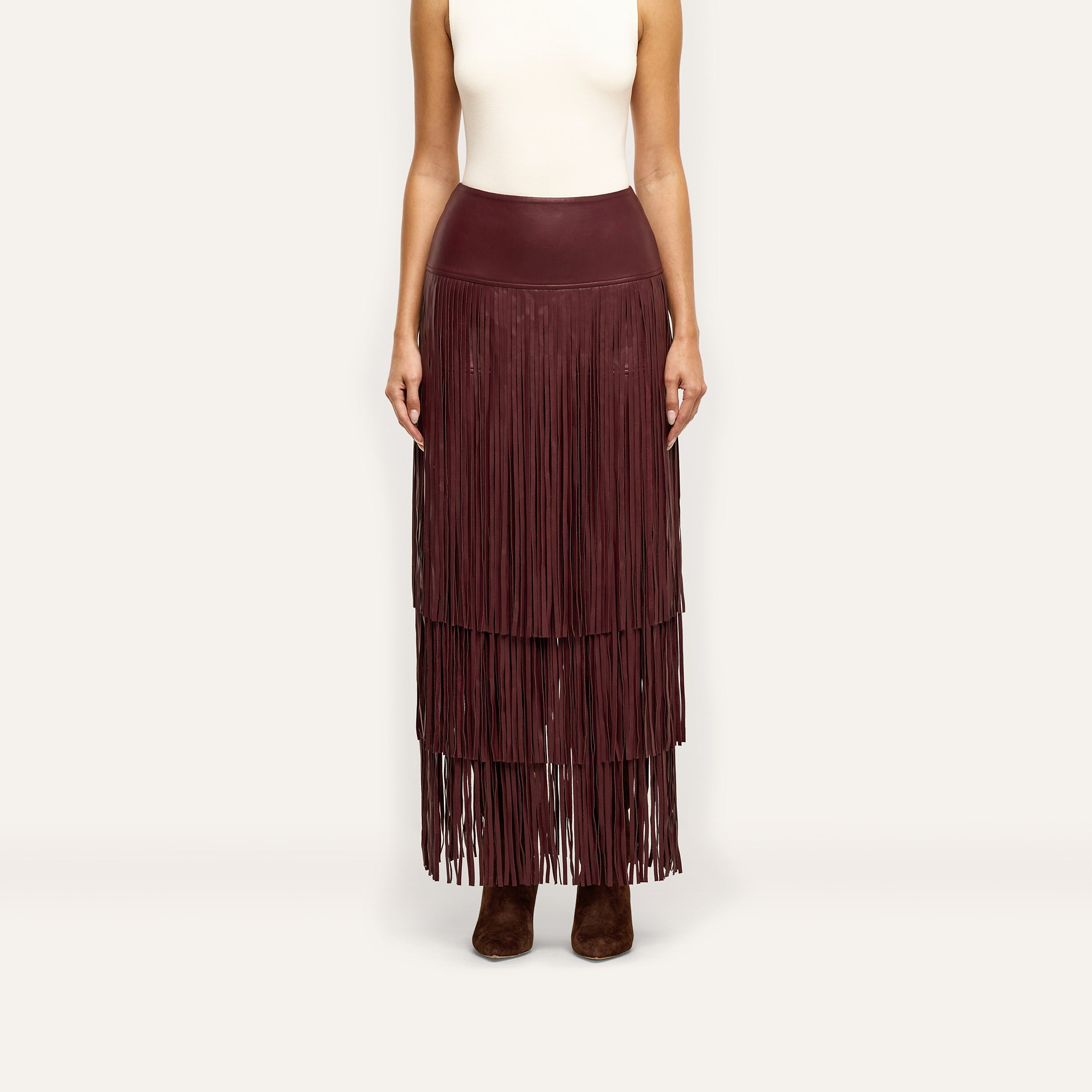 The Karoline Fringe Skirt is a floor-length, deep red tiered fringe skirt worn with a white sleeveless top and dark boots.