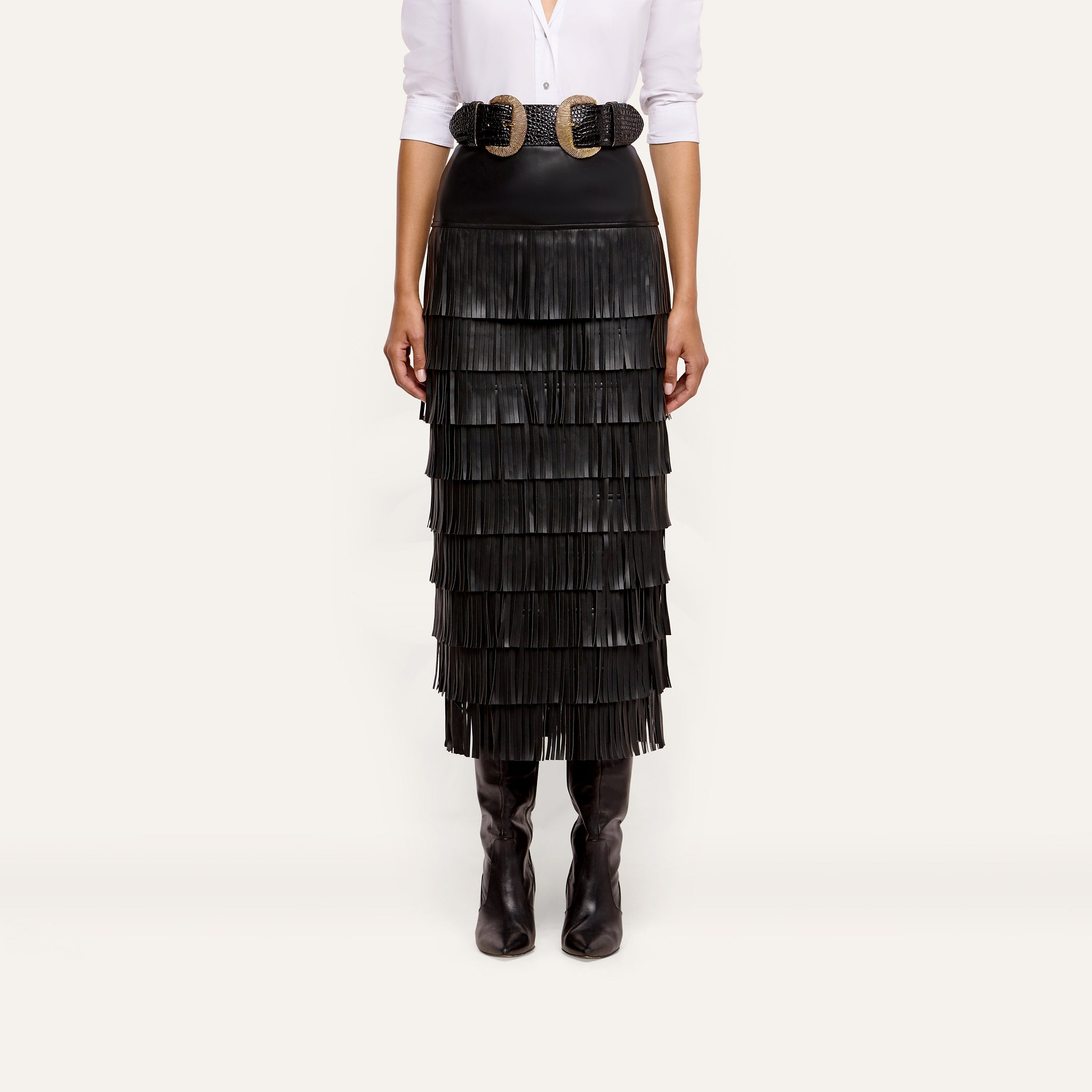Sevigne Fringe Skirt in black, featuring layered fringe and worn with a double-buckle belt and tall boots.