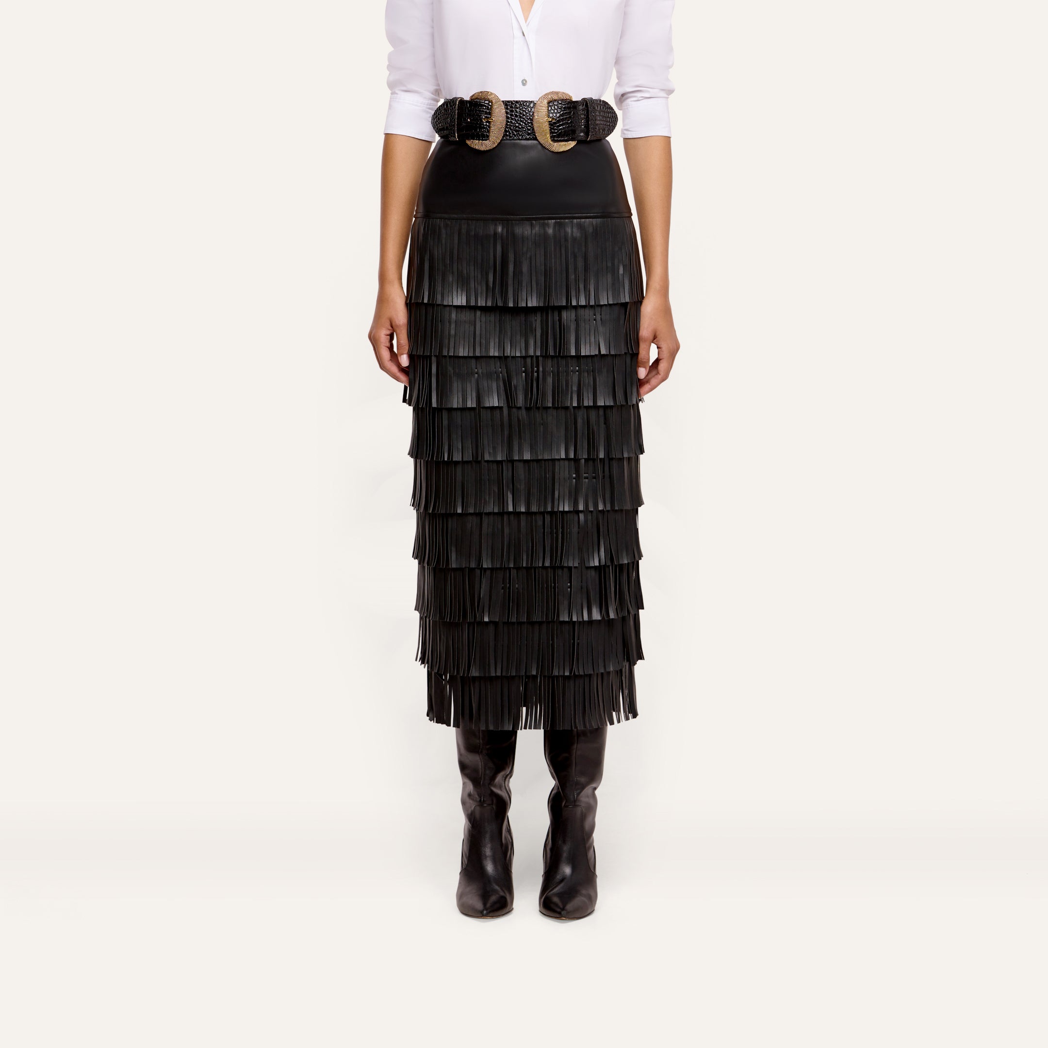 Sevigne Fringe Skirt in black, featuring layered fringe and worn with a double-buckle belt and tall boots.