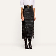 A person wearing a white button-down shirt, a double-buckle belt, and a Sevigne Fringe Skirt in tiered black.