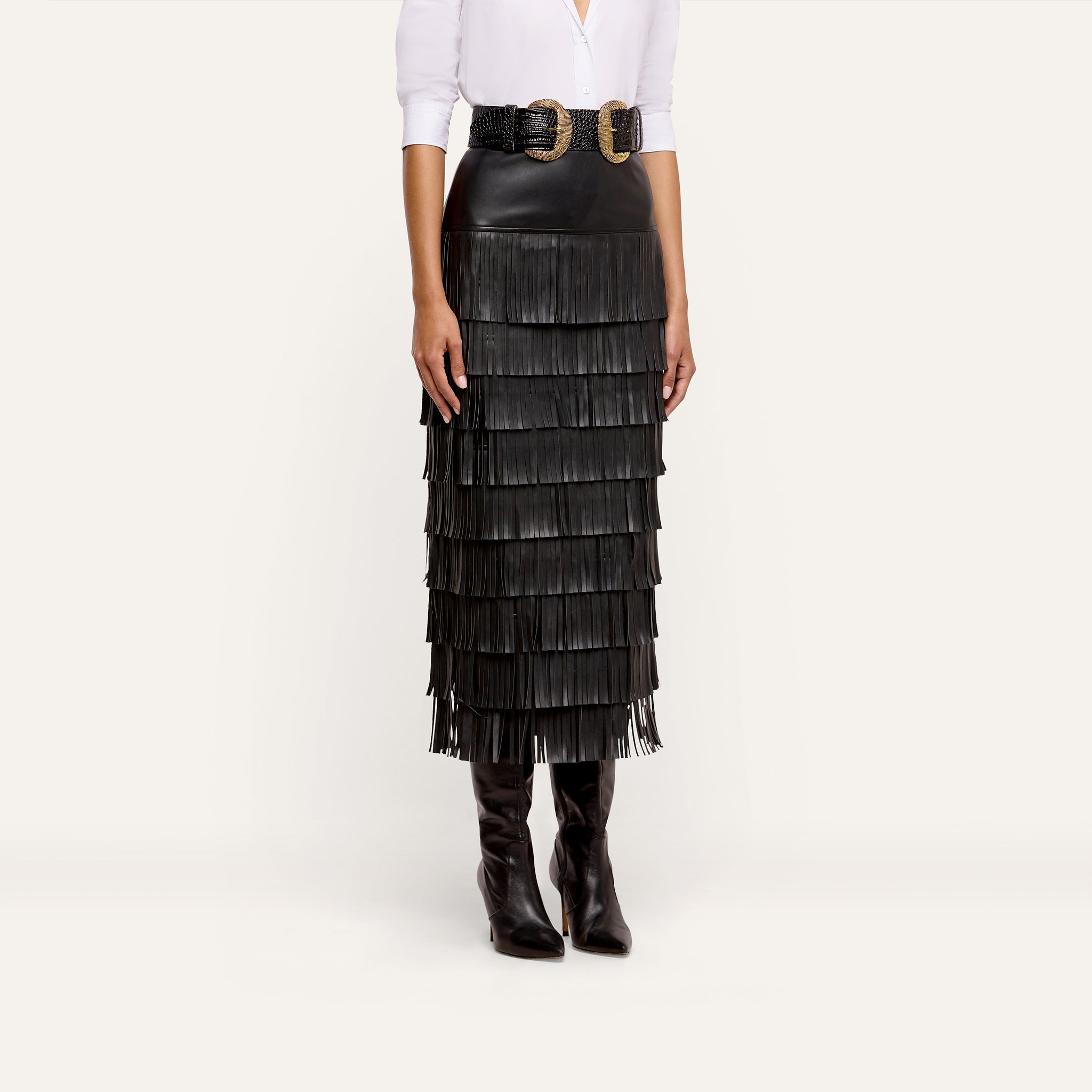 A person wearing a white button-down shirt, a double-buckle belt, and a Sevigne Fringe Skirt in tiered black.