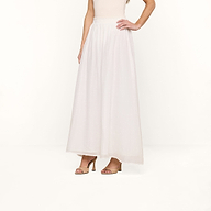 A woman wearing the Evangelina Maxi Skirt in white and nude high-heeled sandals stands against a plain white background, with her upper body partially out of frame.