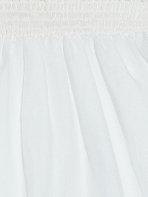 Close-up of the Evangelina Maxi Skirt shows its white, breathable fabric with ruched detailing at the top and soft, flowing pleats below—perfect for summer with its lightweight, slightly sheer material.