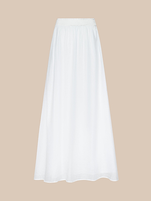 The Evangelina Maxi Skirt is a white, lightweight, and slightly sheer A-line summer skirt with an elastic waistband, shown against a plain beige background.