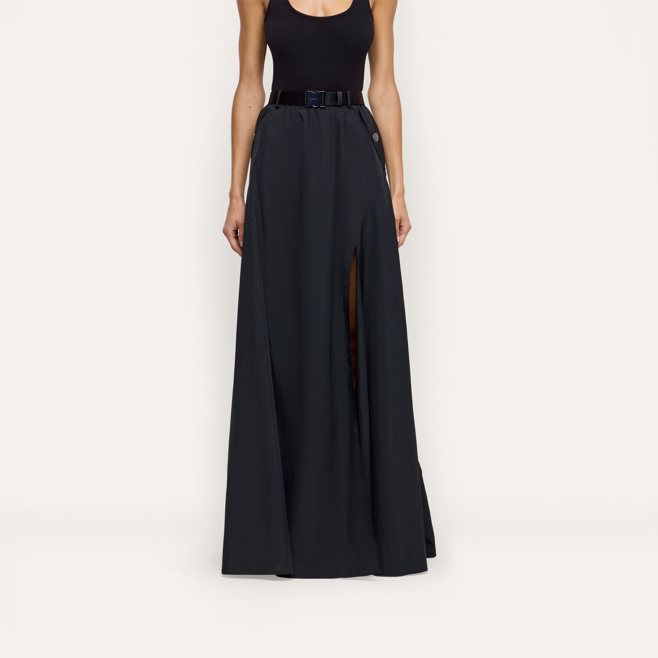Sylas Nylon Skirt in black water-repellant nylon, featuring a high front slit and a buckled belt at the waist.