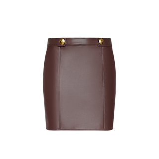 The Nolina Mini Skirt, crafted from mahogany brown vegan leather and featuring gold button details at the waistband, is displayed against a plain white background.