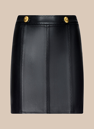 Arlena Vegan Leather Mini Skirt in black, featuring vertical stitching, two gold buttons at the waist, and gold hardware, displayed against a neutral beige background.
