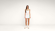 A woman in a white tennis outfit with teal accents, sunglasses, and sneakers stands against a plain white background.