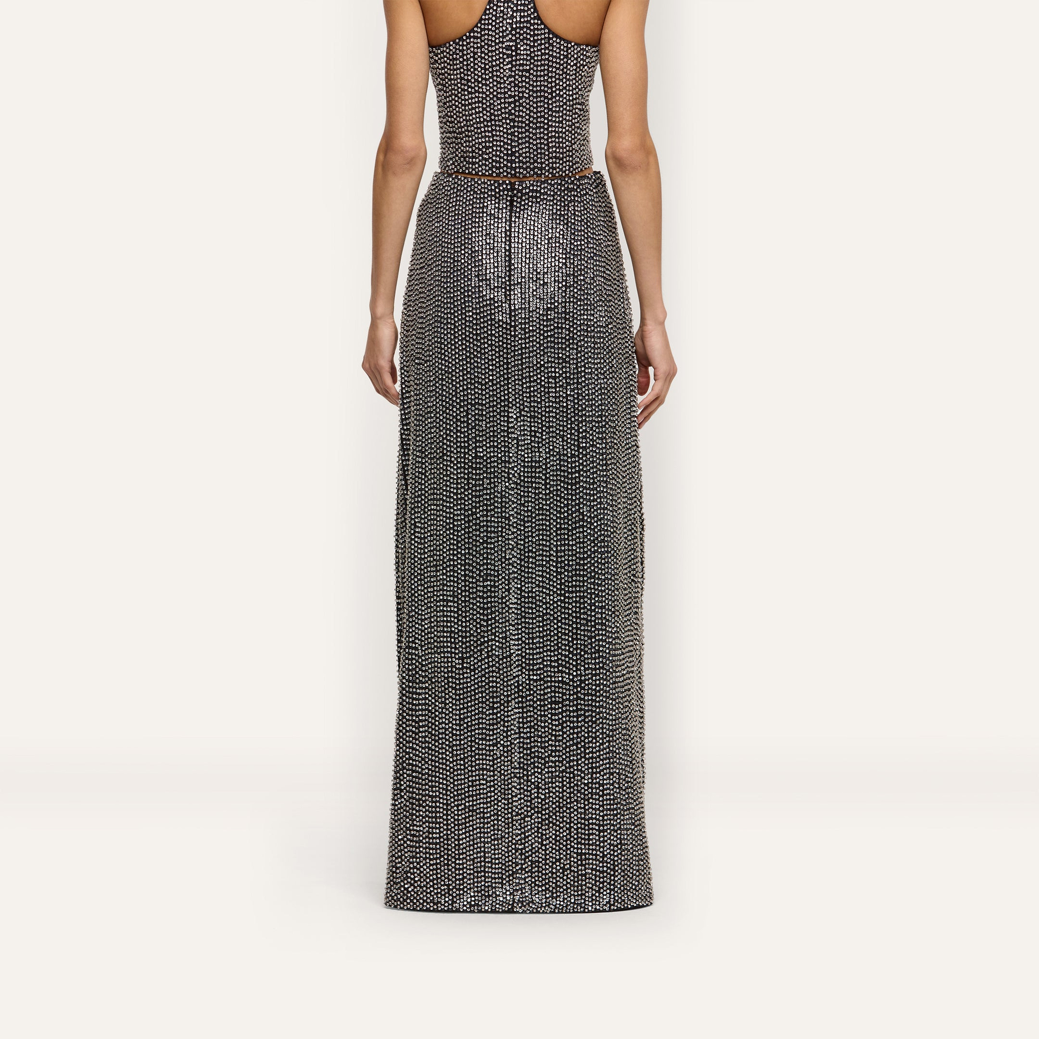 A person seen from behind wearing a hand-beaded Zeta Beaded Maxi Skirt with a matching sleeveless top.