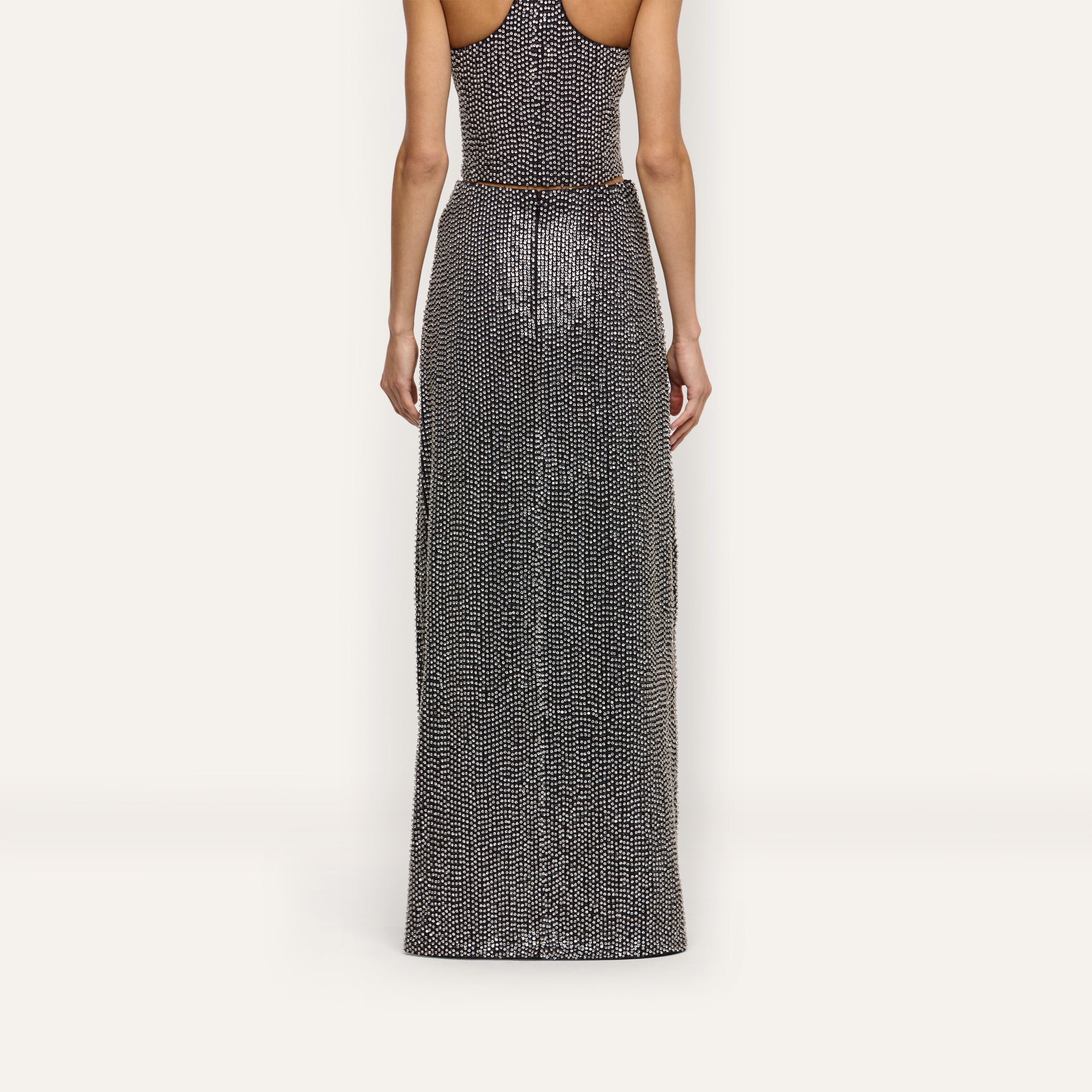 A person seen from behind wearing a hand-beaded Zeta Beaded Maxi Skirt with a matching sleeveless top.