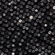 Close-up of the black hand-beaded fabric of the Zeta Beaded Maxi Skirt, densely covered in rows of round, clear, faceted beads.