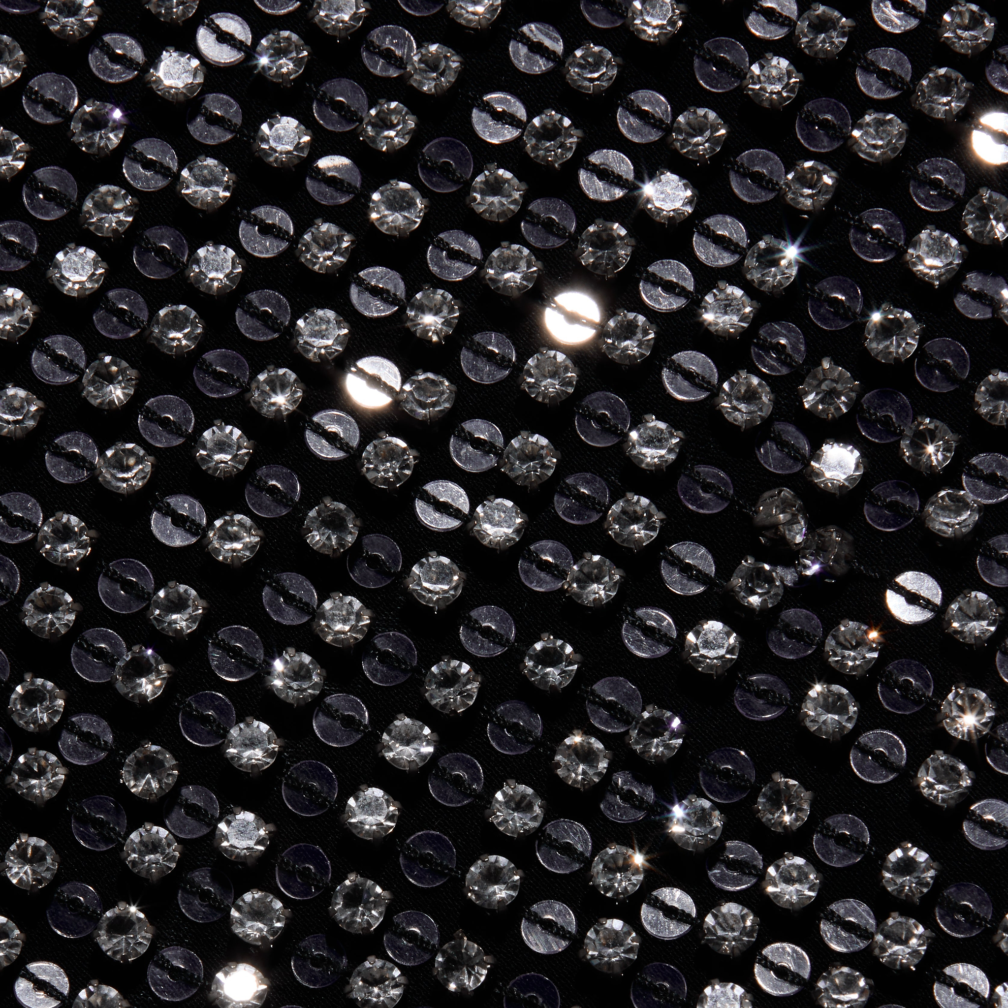Close-up of the black hand-beaded fabric of the Zeta Beaded Maxi Skirt, densely covered in rows of round, clear, faceted beads.