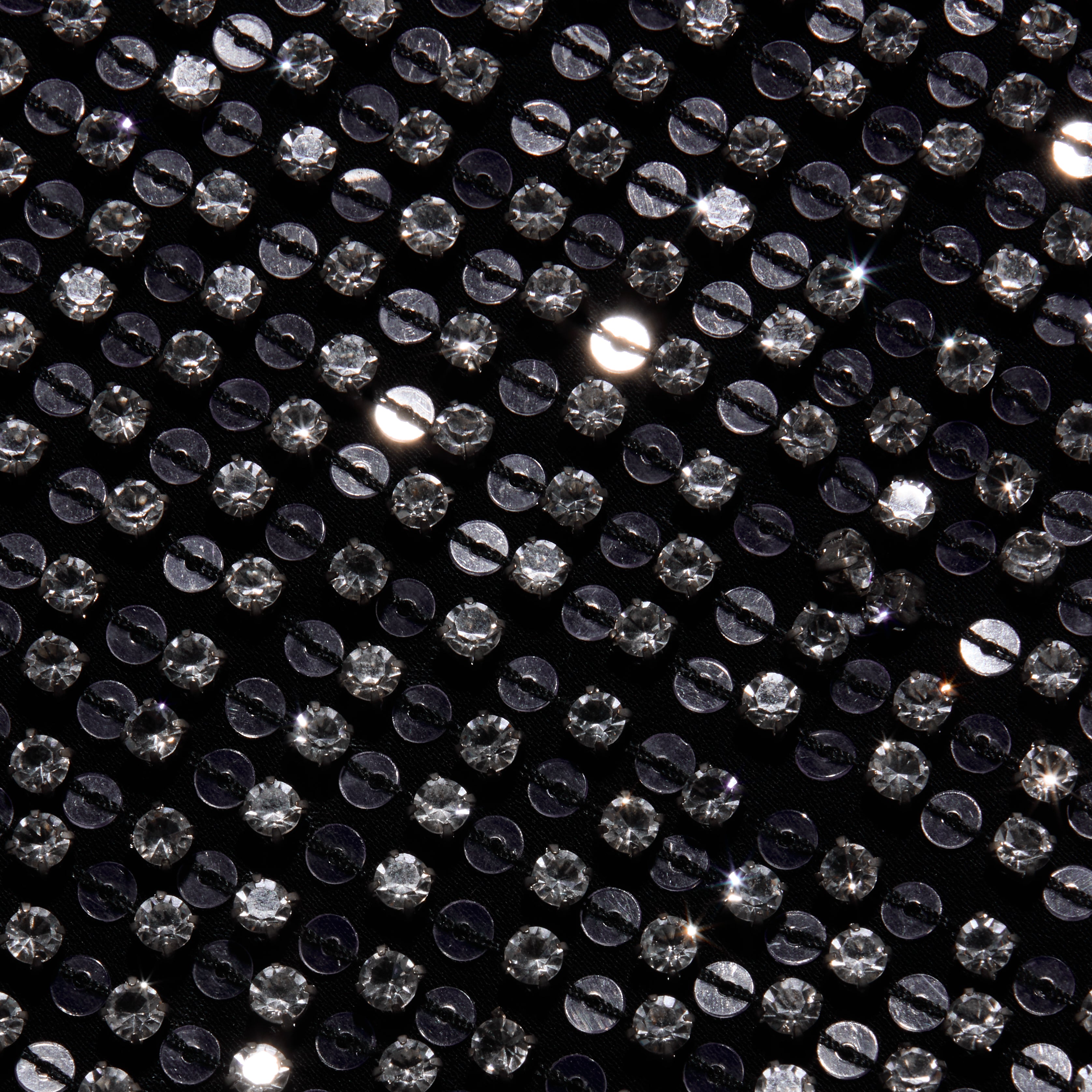 Close-up of the black hand-beaded fabric of the Zeta Beaded Maxi Skirt, densely covered in rows of round, clear, faceted beads.