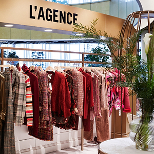 Fashion store interior with 'L'AGENCE' branding and clothing racks.