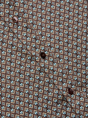 Close-up of the Dani Silk Blouse’s button placket, showing its blue, white, and brown art deco print silk fabric with four dark brown buttons sewn along the seam.