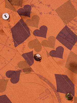 Close-up of the Dani Silk Blouse: a brown-orange silk charmeuse button-down with dark brown hearts and squares, two buttons on the placket, and a subtle overlay of circular, map-inspired lines.