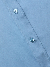 Close-up of a blue mist Dani Silk Blouse fabric with two small, shiny buttons along a stitched seam, shown at a slight diagonal angle.