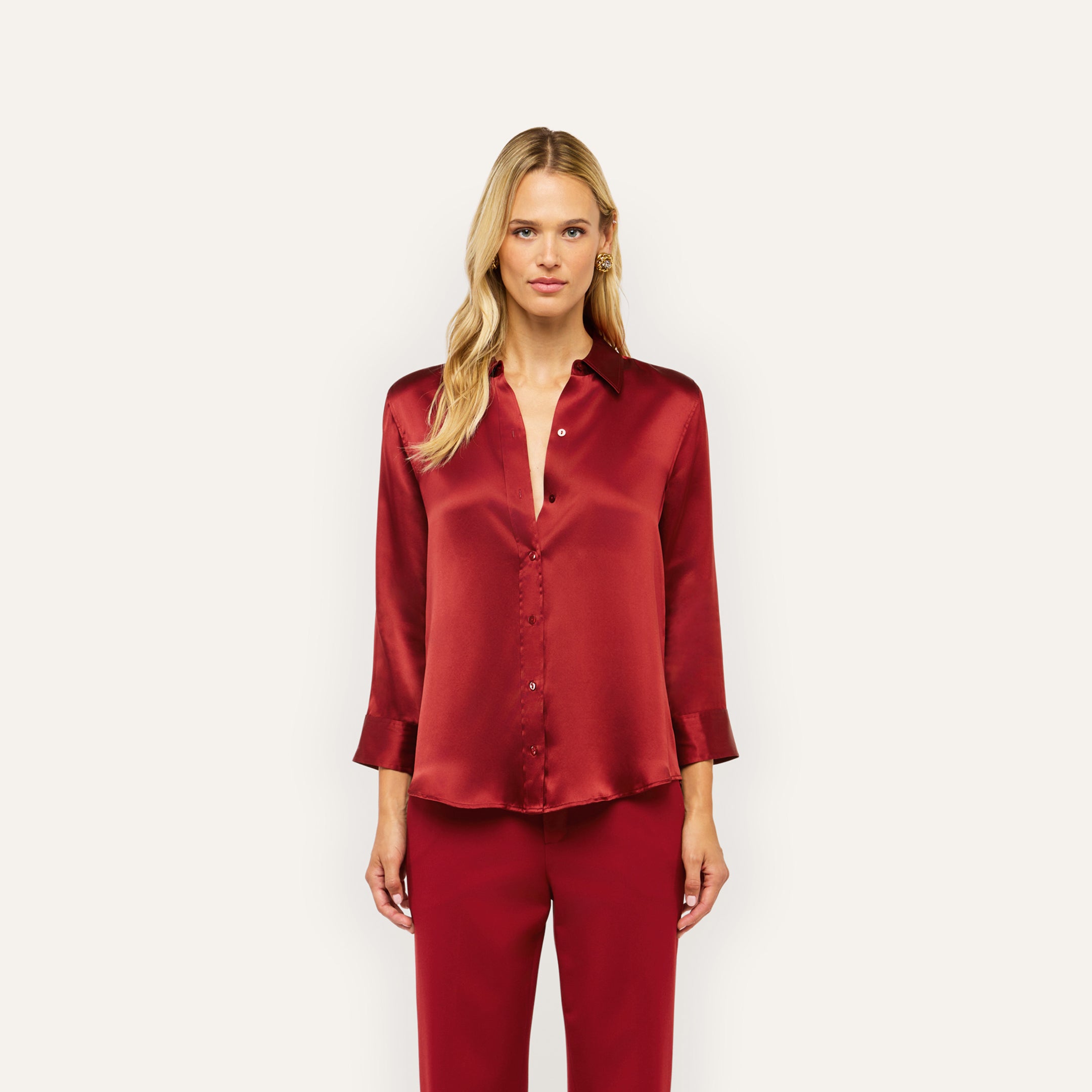 A woman wearing a deep red Dani Silk Blouse in silk charmeuse with matching trousers.