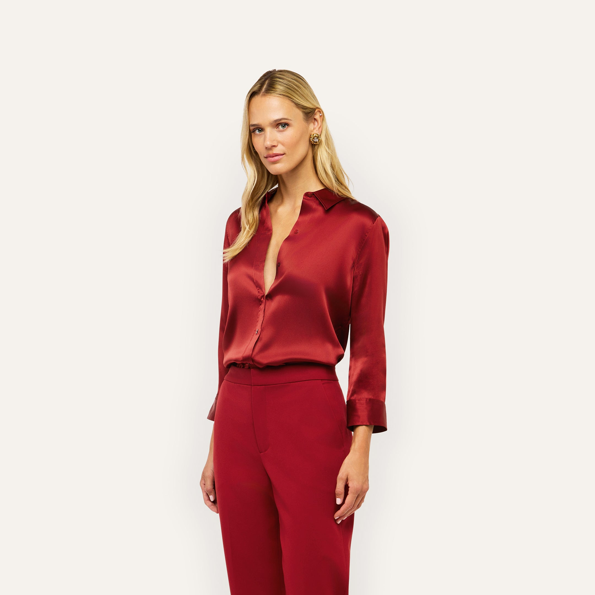 A woman wearing a deep red Dani Silk Blouse and matching trousers.