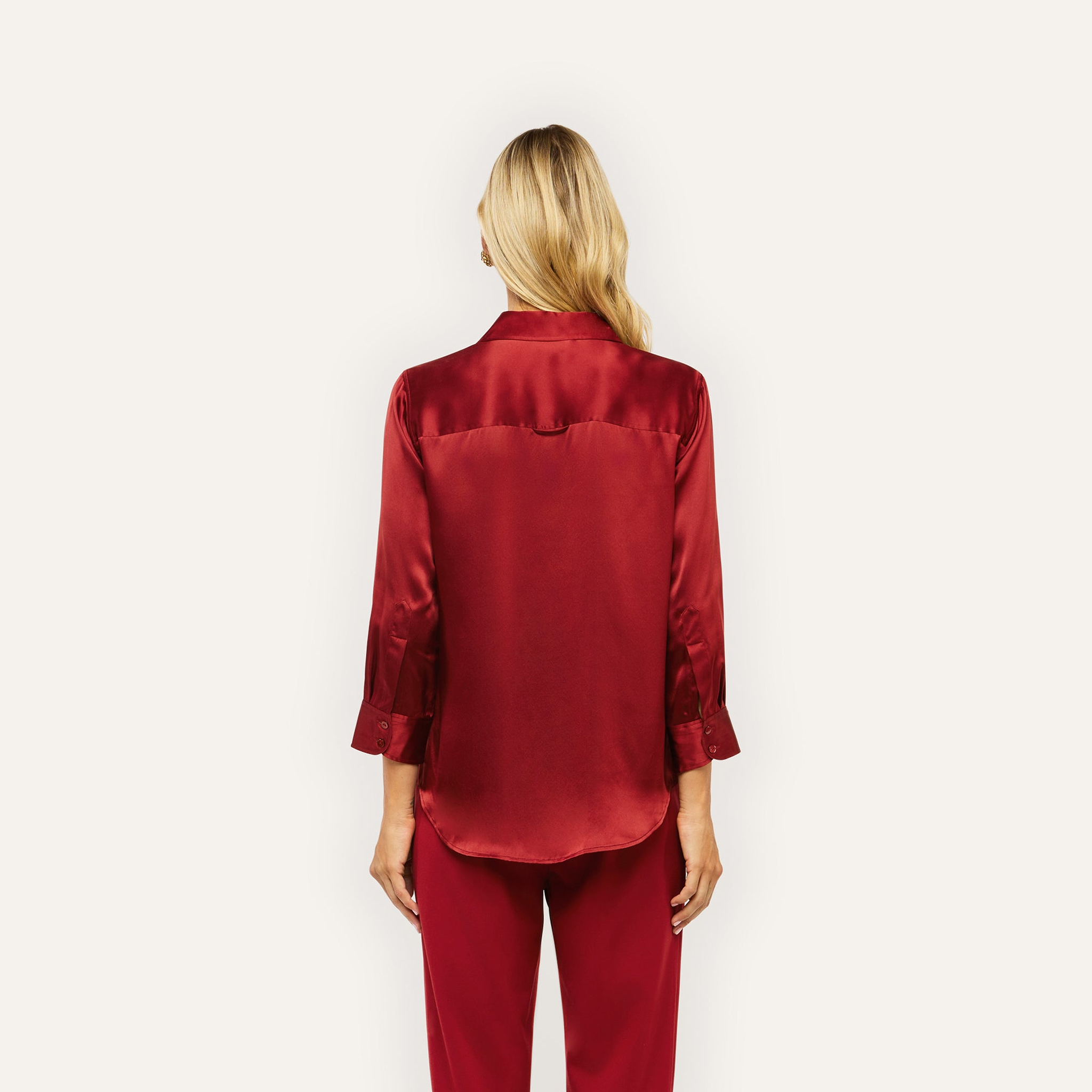 A woman seen from the back wearing a long-sleeved red Dani Silk Blouse and matching silk charmeuse trousers.