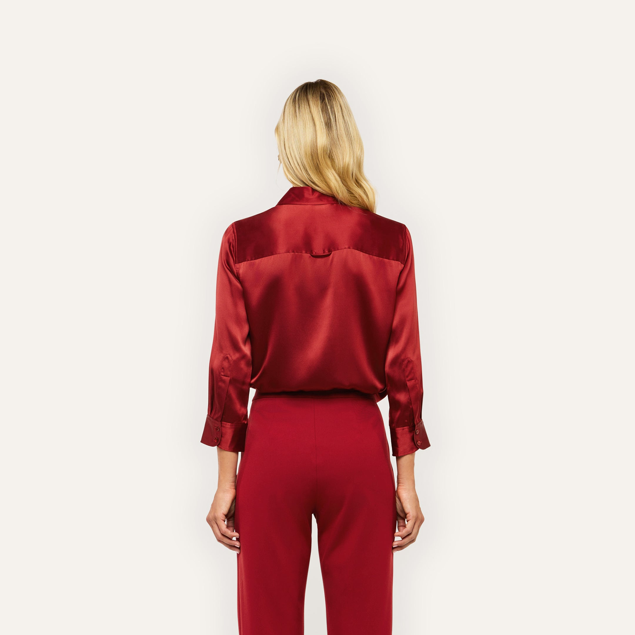 Back view of a person wearing a long-sleeved red silk charmeuse Dani Silk Blouse and matching trousers.