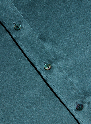 Close-up of the Dani Silk Blouse in cadet blue, featuring an angled seam and three black buttons along the edge.