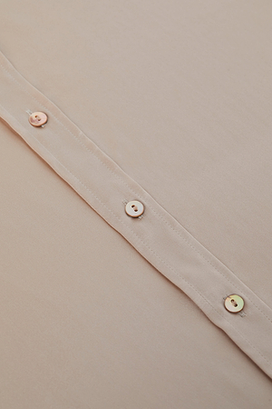 Close-up of the Dani Silk Blouse in light beige silk charmeuse, showing a vertical stitched seam with four small, round, subtly shiny buttons sewn with light thread and evenly spaced along the seam.