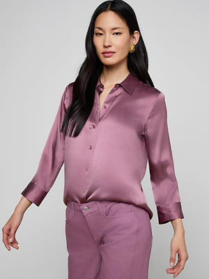 A woman with long dark hair wears the Dani Silk Blouse, a silky mauve button-down with long sleeves, and matching mauve pants, standing against a plain light gray background.