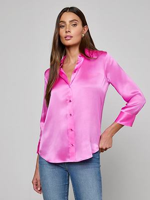A woman with long brown hair wears a fuchsia Dani Silk Blouse with three-quarter sleeves and blue jeans, standing against a plain light gray background.