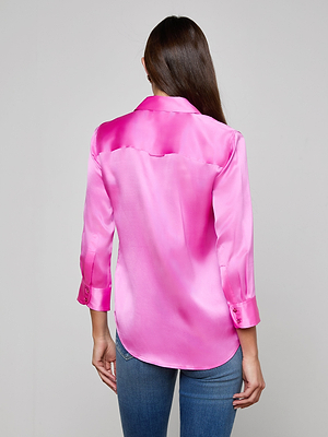 A woman with long brown hair is shown from the back, wearing the Dani Silk Blouse in vibrant fuchsia with rolled sleeves and blue jeans against a plain light background.