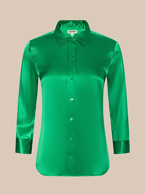 The Dani Silk Blouse, featuring a green satin finish, long sleeves, classic collar, and tailored fit, is showcased against a plain beige background for an elegant and timeless look.