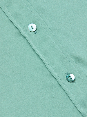 Close-up of the Dani Silk Blouse in light green 100% silk charmeuse, featuring two small, shiny buttons. The smooth texture and elegant sheen emphasize its luxurious quality.