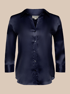 The Dani Silk Blouse, a midnight blue long-sleeve button-down with a collar, is displayed against a beige background.