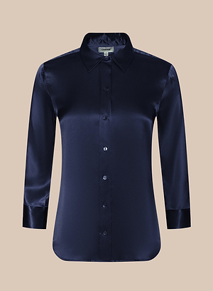 The Dani Silk Blouse, a midnight blue satin button-down with a pointed collar and long sleeves, is displayed against a plain beige background.