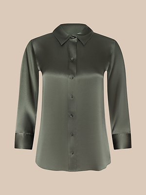 The Dani Silk Blouse is a long-sleeve, smoky olive green satin top with a classic collar and button-down front, shown on a plain beige background.