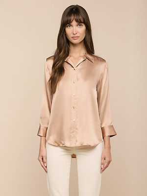 A woman with long brown hair stands facing forward, wearing the Dani Silk Blouse with 3/4 sleeves and cream-colored pants against a beige background.