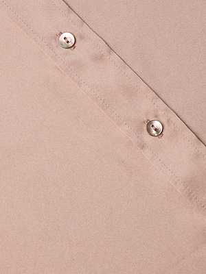Close-up of the Dani Silk Blouse’s light brown silk fabric, showing two silver-toned buttons along a diagonal seam. The smooth texture highlights its delicate craftsmanship, with details suggesting it may feature 3/4 sleeves.