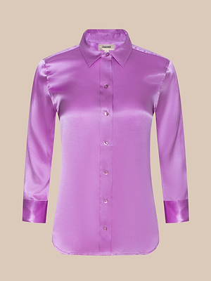 The Dani Silk Blouse, in shiny bright purple with a classic collar and cuffs, has a button-up front and is shown against a beige background.