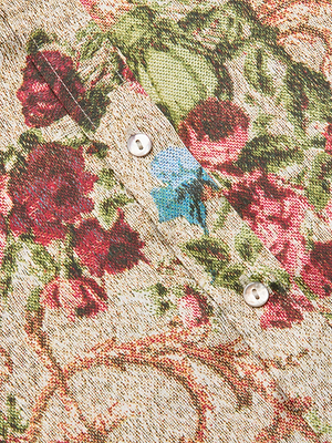 Close-up of the Dani Silk Blouse, featuring a floral tapestry print with red, blue, and green flowers on a textured beige background. This button-down showcases white buttons and a visible pocket seam.