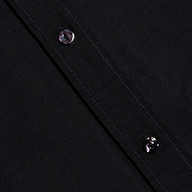 Close-up of the Dani Cotton-Silk Blouse fabric in black, featuring two black buttons along a diagonal seam with visible stitching.