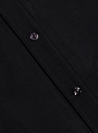 Close-up of a black Dani Cotton-Silk Blouse with two black buttons visible along a seam, positioned diagonally across the image.