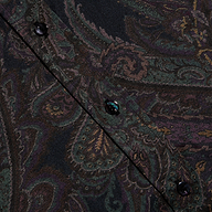 Close-up of the Dani Silk Blouse’s paisley-patterned silk fabric in dark colors, highlighting a diagonal seam with black buttons.