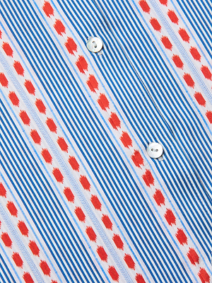 Close-up of the Dani Silk Blouse in silk charmeuse, showcasing blue and white vertical stripes, red geometric patterns, two white buttons, and a diagonal repeating design for a striking effect.