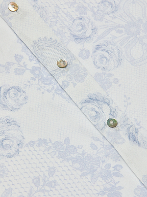 Close-up of the Dani Silk Blouse in ivory and blue lace print, featuring pearl-like buttons along a diagonal seam. Roses and mesh details add to the blouse’s delicate, elegant silk button-down style.
